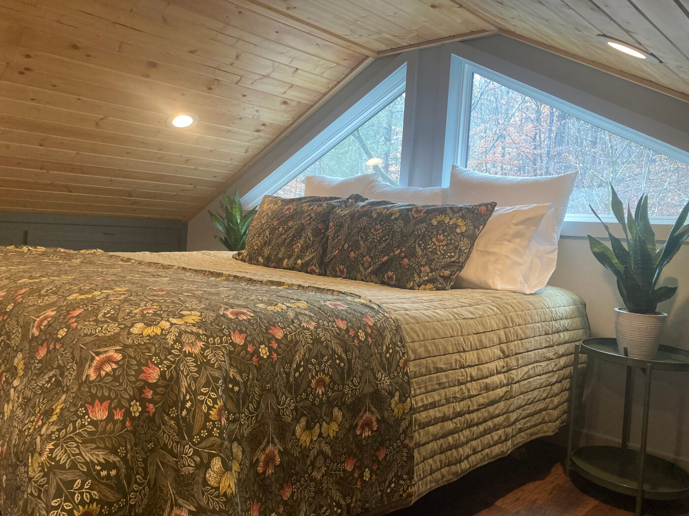 The loft bedroom, with the bed tucked under triangular windows