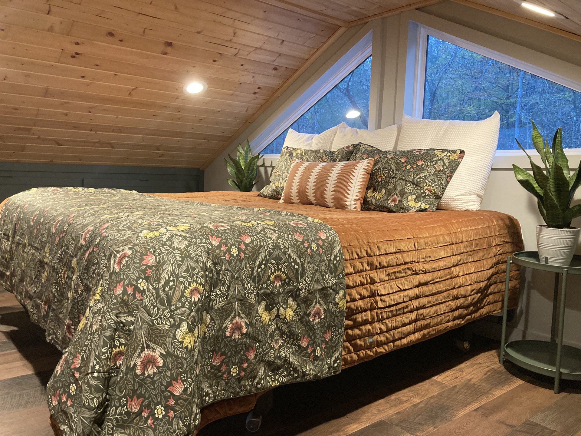 Loft bedroom with a plush king bed under the sloped wooden ceiling
